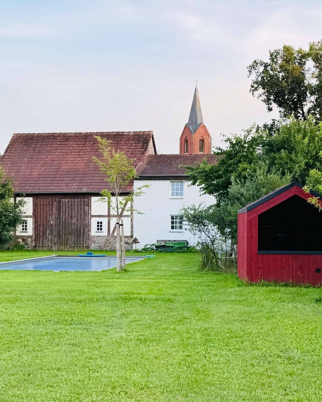 Barn Nordic in schönem Rot in idyllischer Gartenlandschaft passend zu roten Backstein