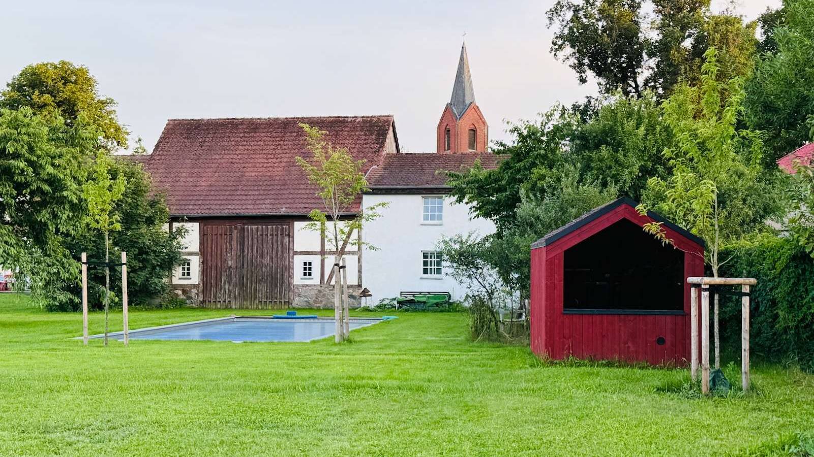 Barn Nordic in schönem Rot in idyllischer Gartenlandschaft passend zu roten Backstein