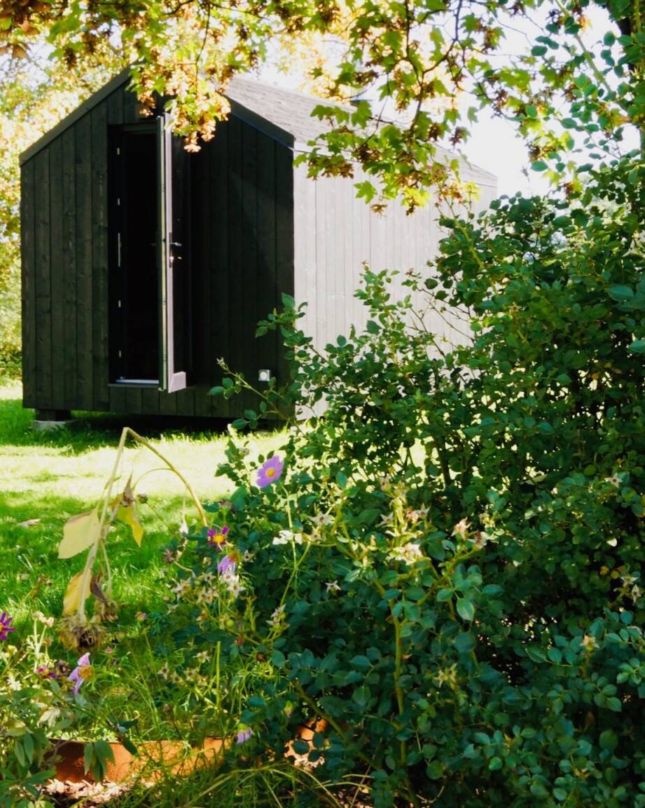 Gartensauna mit Vorraum und Holzofen zwischen Blumen scaled uai – ManoKin Gartensauna mit Vorraum und Holzofen zwischen Blumen